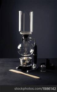 Vacuum coffee maker also known as vac pot, siphon or syphon coffee maker on rustic black stone table.