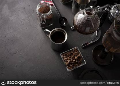 Vacuum coffee maker also known as vac pot, siphon or syphon coffee maker. Metallic cup and toasted coffee beans on rustic black stone table. Copy space for your text