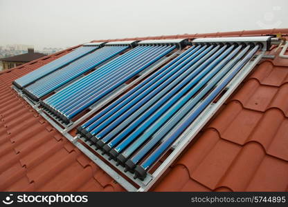 Vacuum collectors- solar water heating system on red roof of the house.