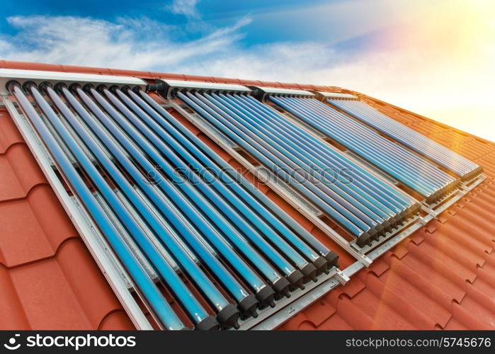 Vacuum collectors- solar water heating system on red roof of the house.