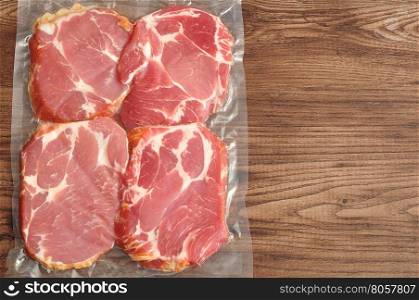 Vacuum packed meat displayed on a wooden background