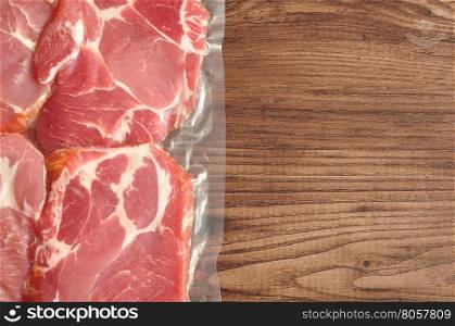 Vacuum packed meat displayed on a wooden background