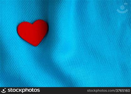 Valentine&#39;s day background. Red decorative heart on abstract blue wavy folds cloth or textile elegant material