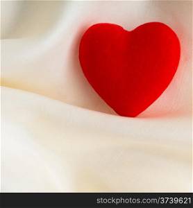 Valentine&#39;s day or wedding. Red wooden decorative heart on abstract white background luxury cloth silk or satin textile with copy space