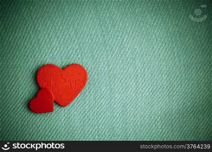 Valentine&#39;s day or wedding. Red wooden decorative two hearts on abstract green cloth textile background with copy space