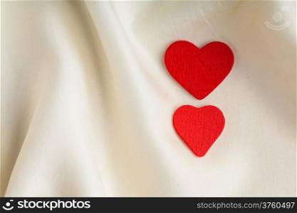 Valentine&#39;s day or wedding. Red wooden decorative two hearts on abstract white background luxury cloth silk or satin textile with copy space