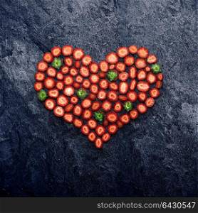 Valentine and love concept, creative still life of heart made of sliced strawberries, on stone background.