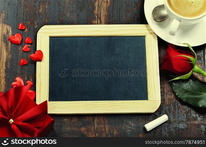 Valentine composition with coffee, chalkboard and flowers on wooden background
