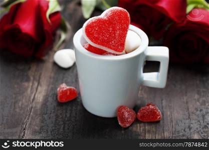 Valentine composition with hearts in a blue cup and roses on wooden background