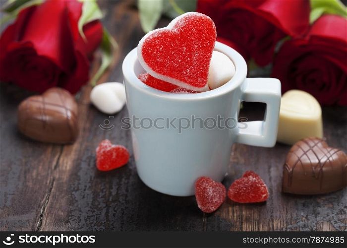 Valentine composition with hearts in a blue cup and roses on wooden background