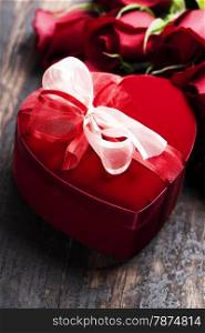 Valentine composition with roses and gift box on wooden background