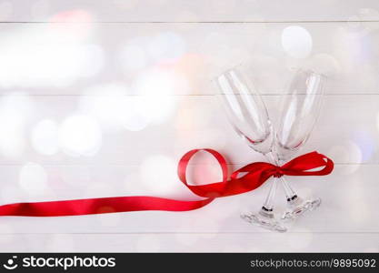 Valentine day concept, wineglass and red ribbon on white wooden table background with bokeh, ch&aign glass on wood desk, top view, flat lay, couples wine glass together, romantic holiday concept.
