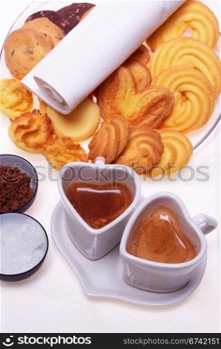 valentine day heart shaped espresso coffee cappuccino cups with assortment of pastry mignon and white brown and rock sugar over white