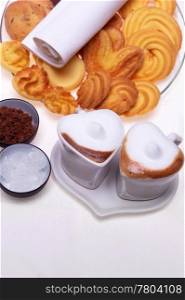 valentine day heart shaped espresso coffee cappuccino cups with assortment of pastry mignon and white brown and rock sugar over white