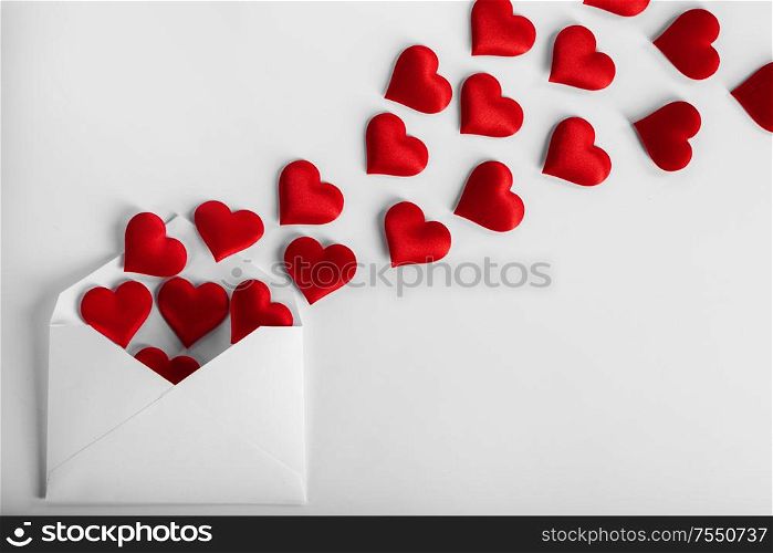 Valentine day love letter, envelope of craft paper with red hearts heap spread on white background.. Valentine day love letter