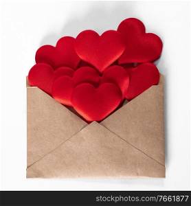 Valentine day love letter, envelope of craft paper with red hearts heap spread on white background.. Valentine day love letter