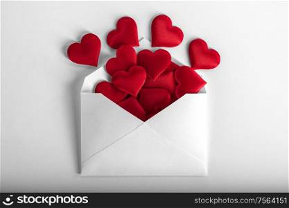 Valentine day love letter, envelope of white paper with red hearts heap spread on white background.. Valentine day love letter