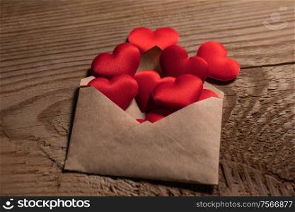 Valentine day love letter, envelope with red hearts heap spread on wooden background.. Valentine day love letter