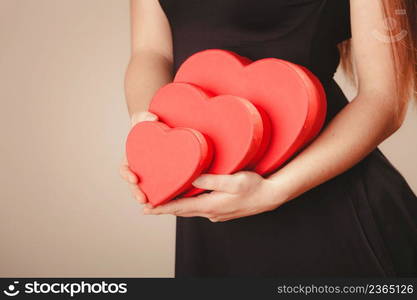 Valentine day. Woman in black holding three hearts boxes gifts presents. Part body of elegant model with valentines symbol sign. Studio shot.. Woman with valentines boxes