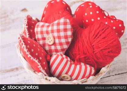 Valentine decorations: textile red hearts in white basket on the shabby table. Hearts on the branch