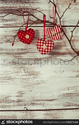 Valentine decorations: textile red hearts on the branch. Hearts on the branch