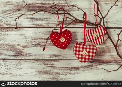 Valentine decorations: textile red hearts on the branch. Hearts on the branch