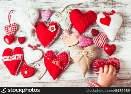 Valentine handmade hearts on the shabby wooden table and child&#39;s hand