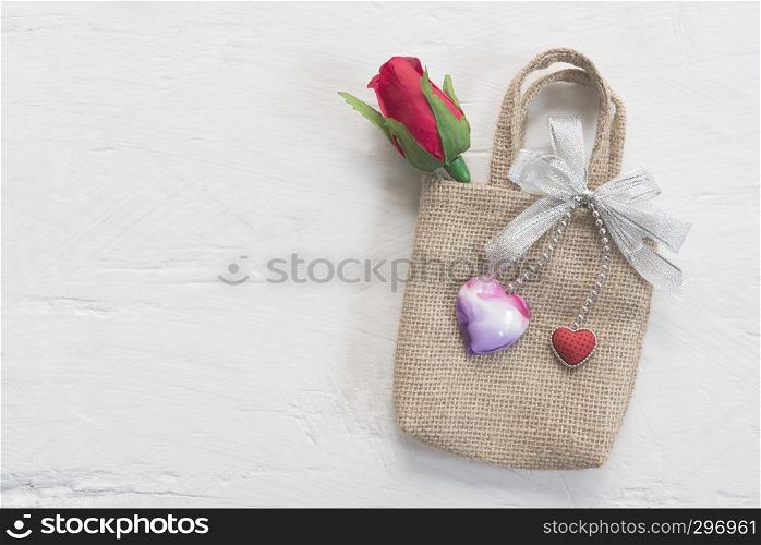 Valentine, love and wedding background concept. Red rose and hearts on small bag put on white wood table. Picture for add text message. Backdrop for design art work.