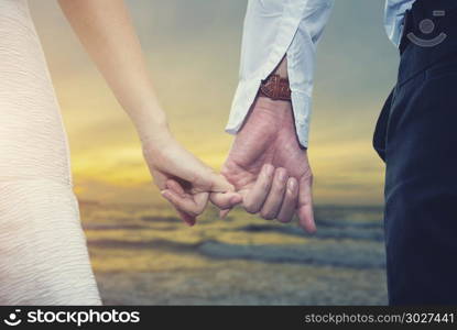 Valentine, love and wedding concept. Closeup of loving couple ho. Valentine, love and wedding concept. Closeup of loving couple holding hands while walking on the beach at sunset. Picture for add text message. Backdrop for design art work.