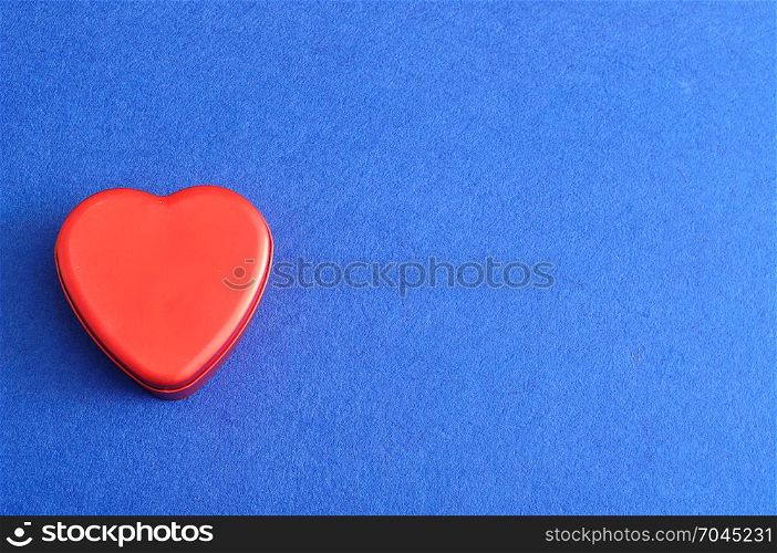 Valentine&rsquo;s Day. A red heart shape tin isolated on a blue background