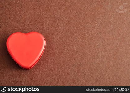 Valentine&rsquo;s Day. A red heart shape tin isolated on a brown background