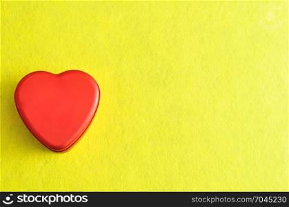 Valentine&rsquo;s Day. A red heart shape tin isolated on a yellow background