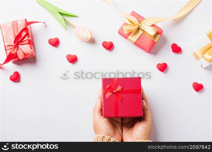 Valentine&rsquo;s day and birthday. Woman hands holding gift or present box decorated and red heart surprise on white background, Female&rsquo;s hand hold gift box package in craft paper Top view flat lay