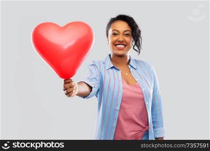 valentine&rsquo;s day and people concept - happy african american young woman with red heart-shaped balloon over grey background. african american woman with heart-shaped balloon