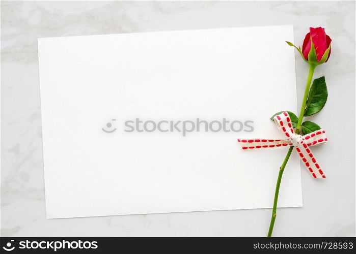 Valentine's day background, template, Red rose and blank white paper on white marble background with copy space for text, top view, flat lay