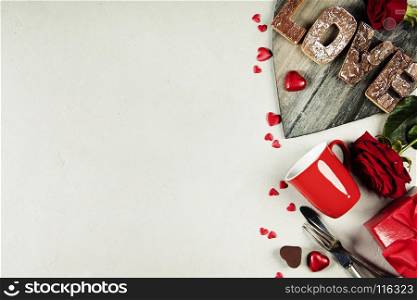 Valentine's day background with chocolate, fork, knife, roses, gifts and love wooden letters.Valentines day concept. Top view. Copy space.