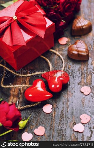 Valentine&rsquo;s day composition with hearts, gift, chocolate and flowers on wooden background