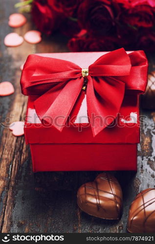 Valentine&rsquo;s day composition with hearts, gift, chocolate and flowers on wooden background