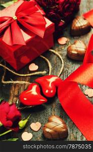 Valentine&rsquo;s day composition with hearts, gift, chocolate and flowers on wooden background