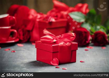 Valentine&rsquo;s Day concept. Gift with red bow on the wooden background. Valentines gift boxes tied with a red satin ribbon bow and beautiful roses on rustic background.. Valentine&rsquo;s Day concept. Valentines gift boxes tied with a red satin ribbon bow and beautiful roses on rustic background.