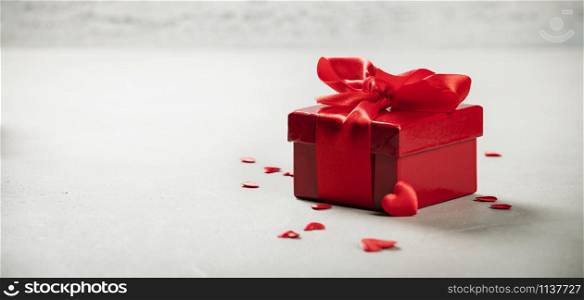 Valentine&rsquo;s Day concept. Gift with red bow on the wooden background Valentines gift box tied with a red satin ribbon bow on rustic background.. Valentine&rsquo;s Day concept. Gift with red bow on the wooden background