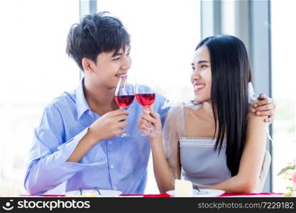 Valentine&rsquo;s day concept,Happy Asian Young sweet couple having romantic the Lunch with clinking toasting wine glasses at the restaurant background.