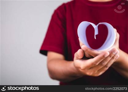 Valentine&rsquo;s day concept. Person holds heart shape paper. Give a love to you. This shot is focused on the edge of paper. Copy space.