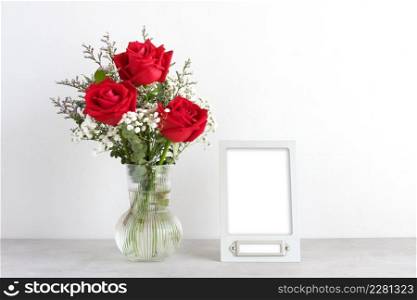 Valentine&rsquo;s day concept, Red roses flower bouquet in glass vase and blank grey vintage frame on table background with copy space , Banner for mock up, template