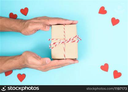 Valentine&rsquo;s Day Concept, Top view Flat lay, have red heart and hand holding gift box on blue background with copy space for your text