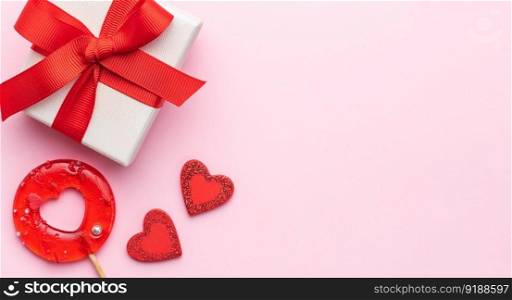 Valentine&rsquo;s Day concept. Top view photo of gift box, heart shaped lollipop on pastel pink background with copy space in the middle. 