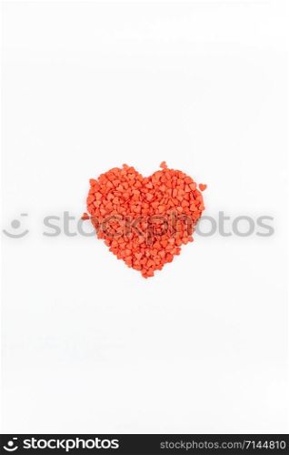 Valentine&rsquo;s Day. Creative holiday concept of love made from red heart shaped sweet confetti. Valentines day top view on white background.