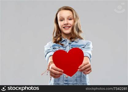 valentine&rsquo;s day, love and people concept - smiling pretty teenage girl in denim jacket holding red heart over grey background. smiling teenage girl with red heart