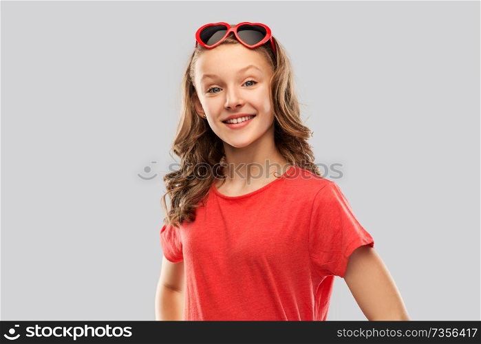 valentine&rsquo;s day, love and people concept - smiling pretty teenage girl with long hair in red heart shaped sunglasses over grey background. happy teenage girl in red heart shaped sunglasses