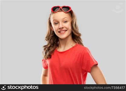 valentine&rsquo;s day, love and people concept - smiling pretty teenage girl with long hair in red heart shaped sunglasses over grey background. happy teenage girl in red heart shaped sunglasses